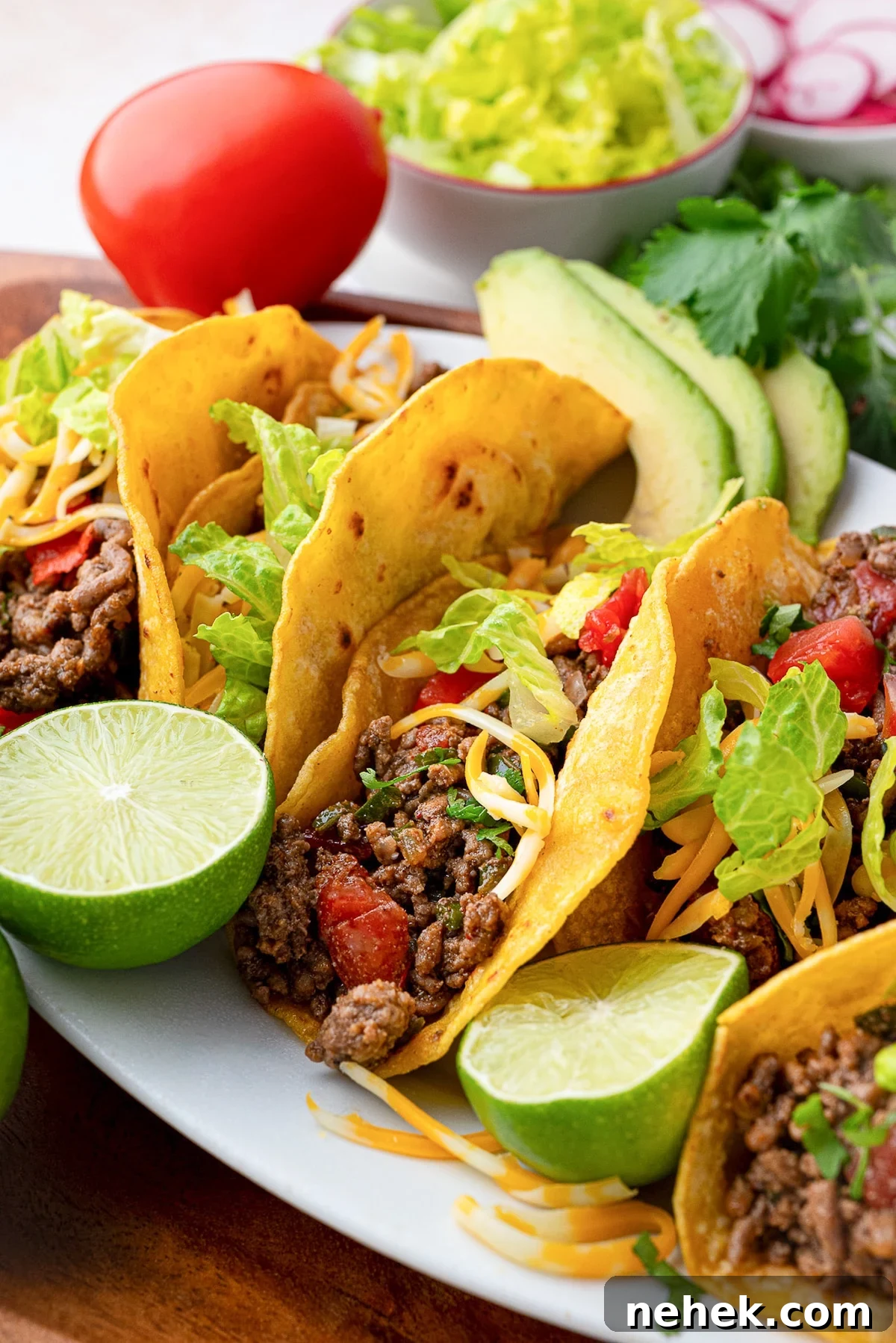 Flavorful Ground Beef Taco Meat Recipe for Tacos & Bowls 6 crispy beef taco meat in shells garnished with Roma tomatoes, limes, cilantro and cheese