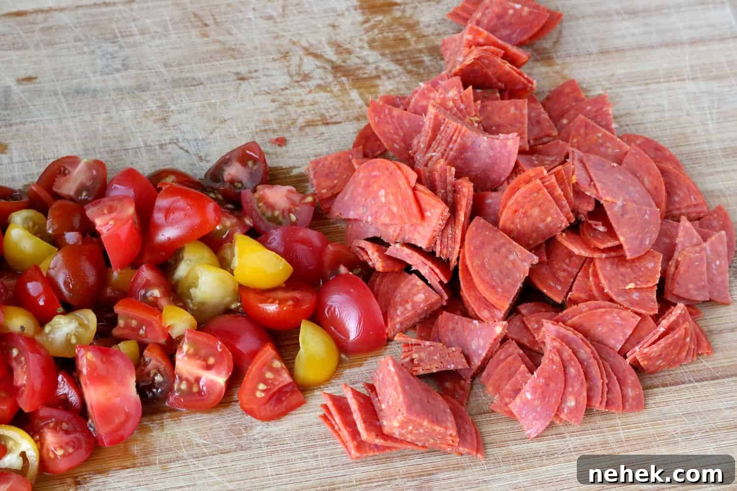 Classic Italian Salad with Homemade Dressing Recipe 3 Quartered cherry tomatoes and pepperoni shown on a wooden cutting board.