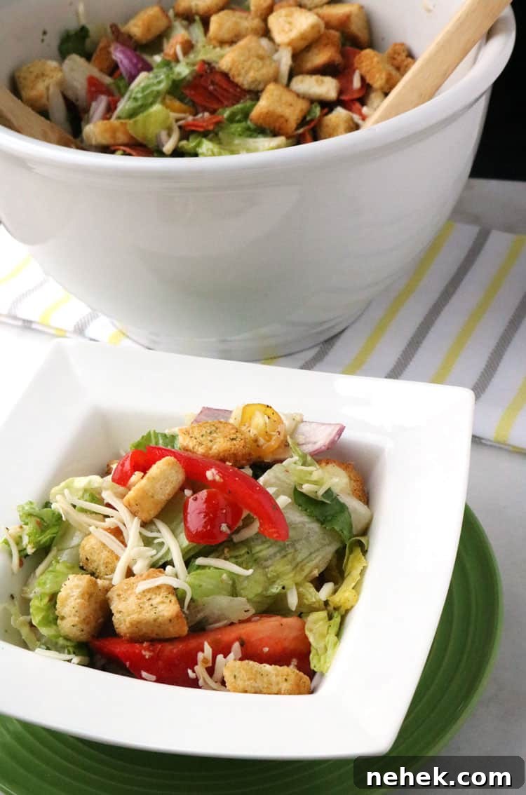 Classic Italian Salad with Homemade Dressing Recipe 7 Italian salad in white mixing bowl, with a portion served in white salad bowl on top of a green plate.