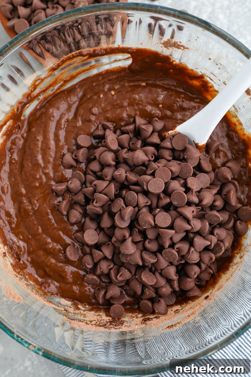 Fudgy Butternut Squash Brownies with Dark Chocolate Swirl 5 A large clear mixing bowl filled with brownie batter with a handful of milk chocolate chips poured on top
