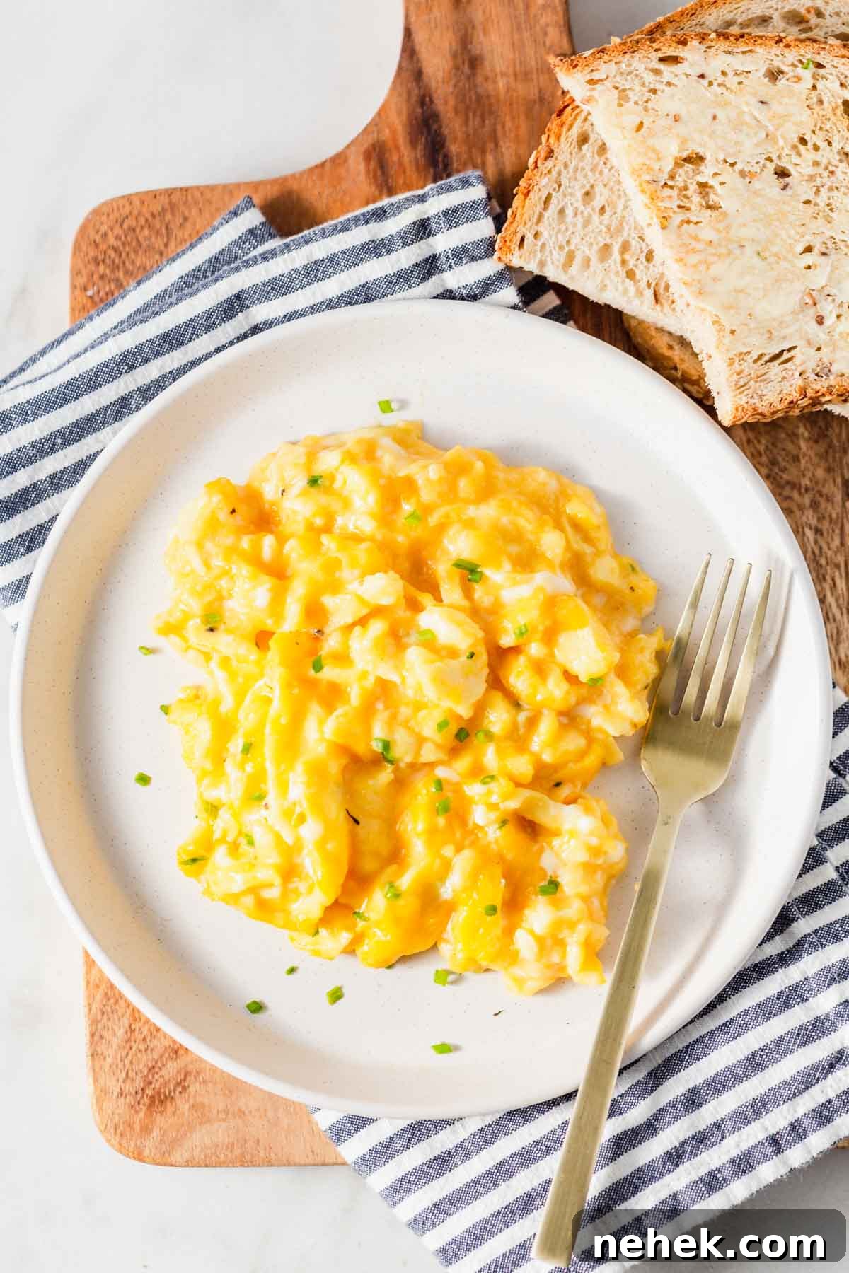 air fryer scrambled eggs on a plate with bread on the side.