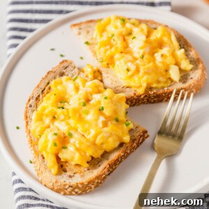 air fryer scrambled eggs on toast with a fork on the side.