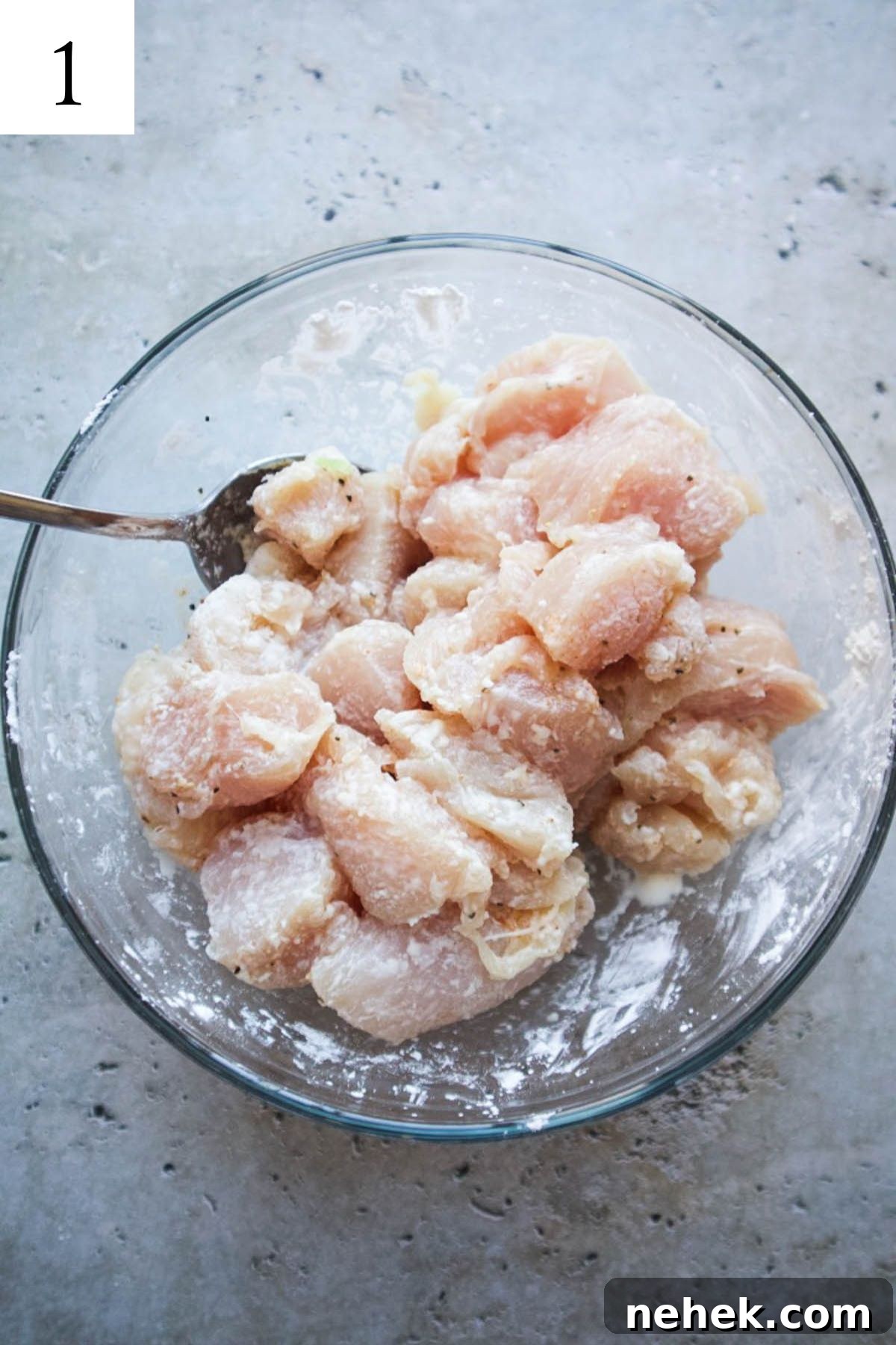glass bowl with chicken pieces mixed in cornstarch, salt, and pepper.