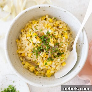 a white spoon resting inside a bowl of corn risotto.