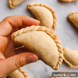 a hand holding a vegan corn empanada