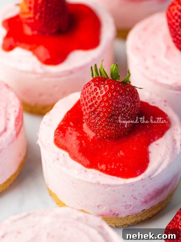 Quick Single-Layer Chocolate Cake Recipe for Perfect Moistness 11 Individual no-bake strawberry cheesecakes topped with strawberry glaze and a fresh strawberry on a parchment paper-lined baking sheet.