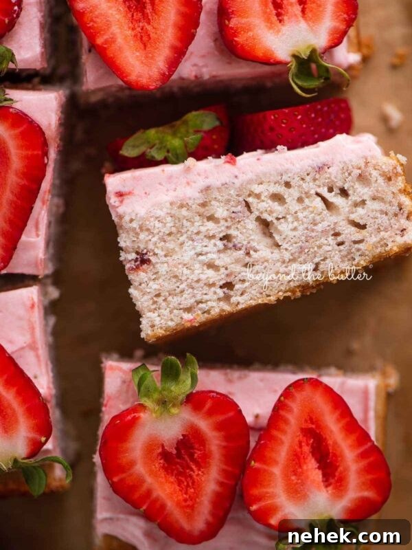 Quick Single-Layer Chocolate Cake Recipe for Perfect Moistness 10 Slices of mini strawberry sheet cake topped with strawberry buttercream frosting and fresh strawberries with one slice on its side.