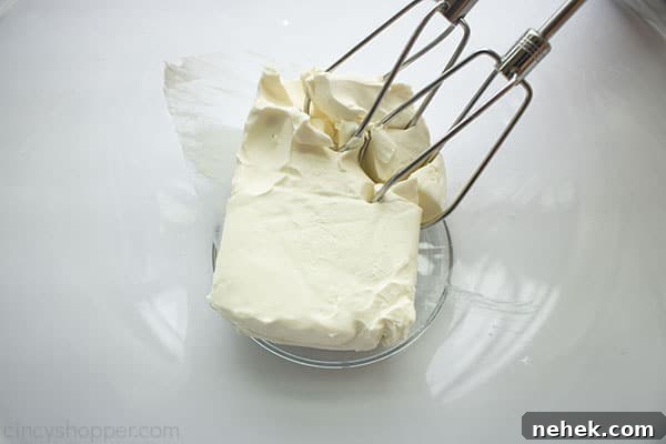 Cream cheese with beaters in a clear bowl.