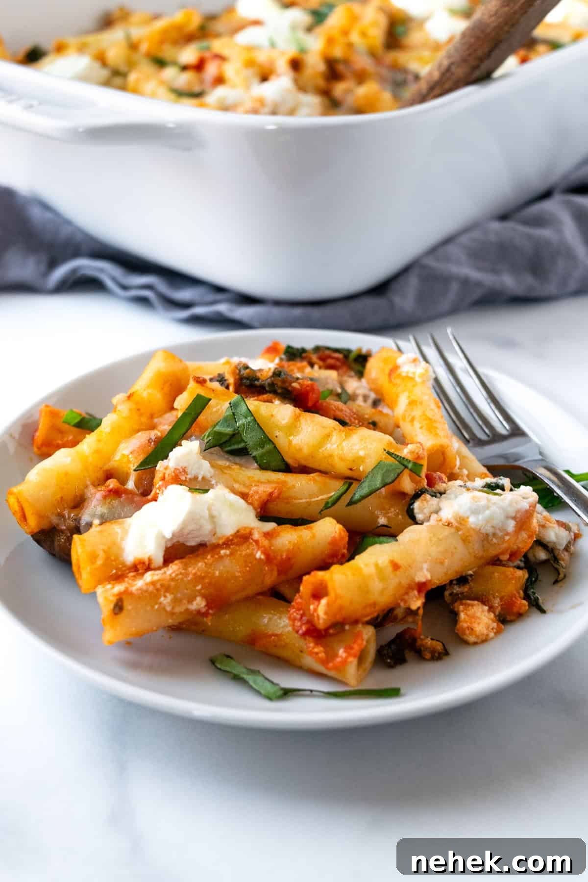 Cheesy Vegetable Baked Ziti with Roasted Tomatoes and Spinach 2 Baked Ziti with Vegetables on a white plate with a fork.