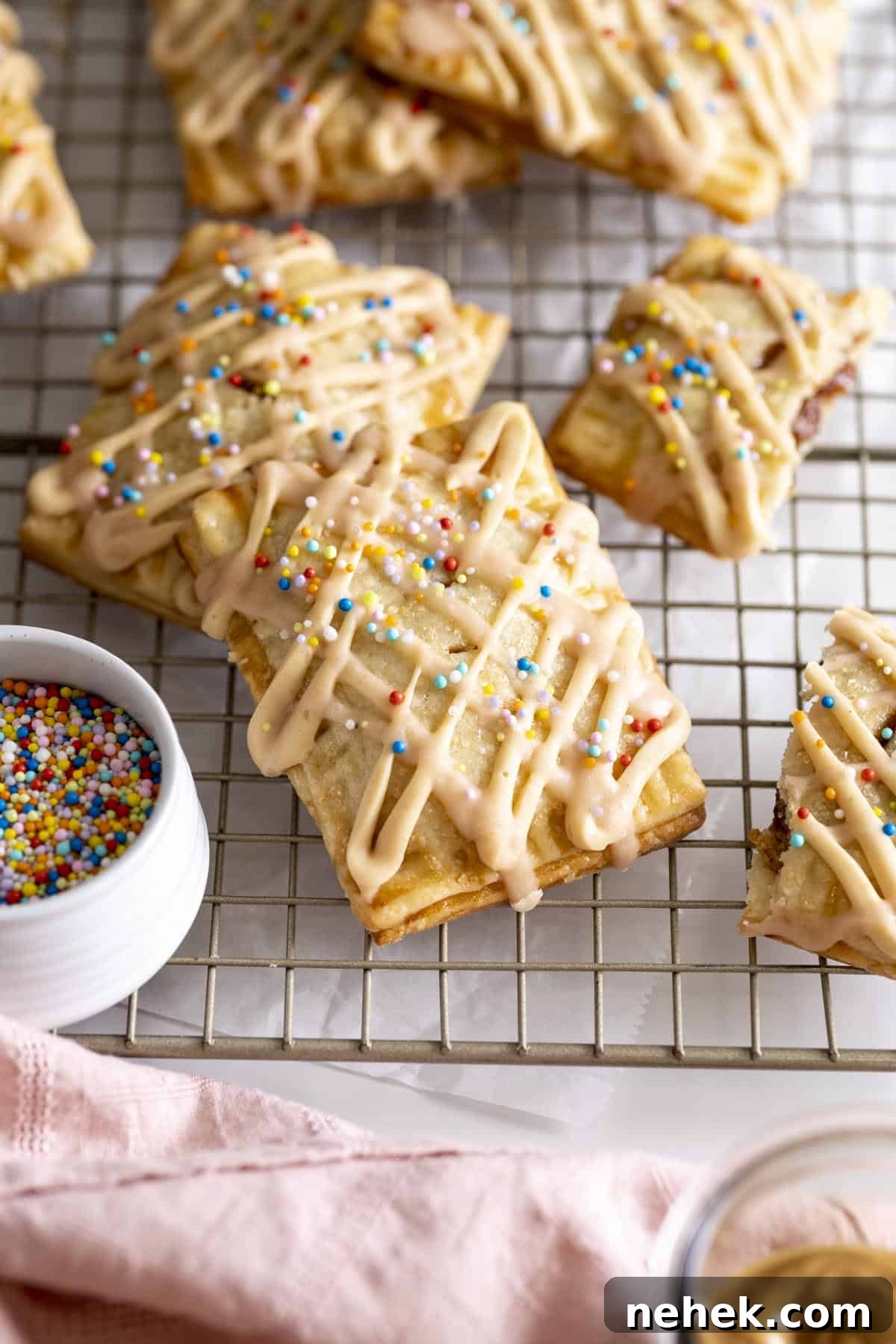 Homemade PB&J pop tarts with glaze and sprinkles on a wire rack.
