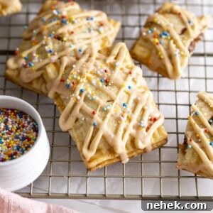 Homemade PB&J pop tarts with glaze and sprinkles on a wire rack.
