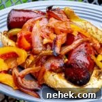 Grilled Sausage with Peppers and Onions on a bun on a gray plate