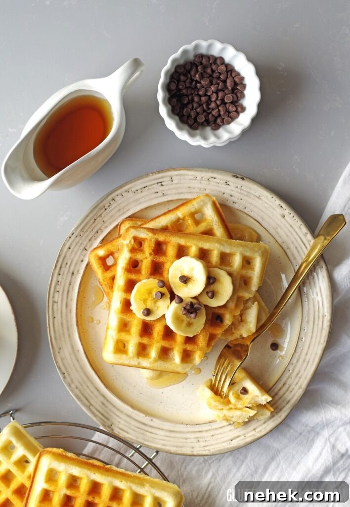 Top-down view of gluten-free waffles topped with bananas and mini chocolate chips on a plate with a fork.