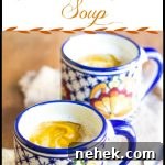 Creamy Spiced Pumpkin Soup Made with Canned Pumpkin 6 A cup of pumpkin soup topped with foamed Half & Half, sitting on a placemat with a spoon.