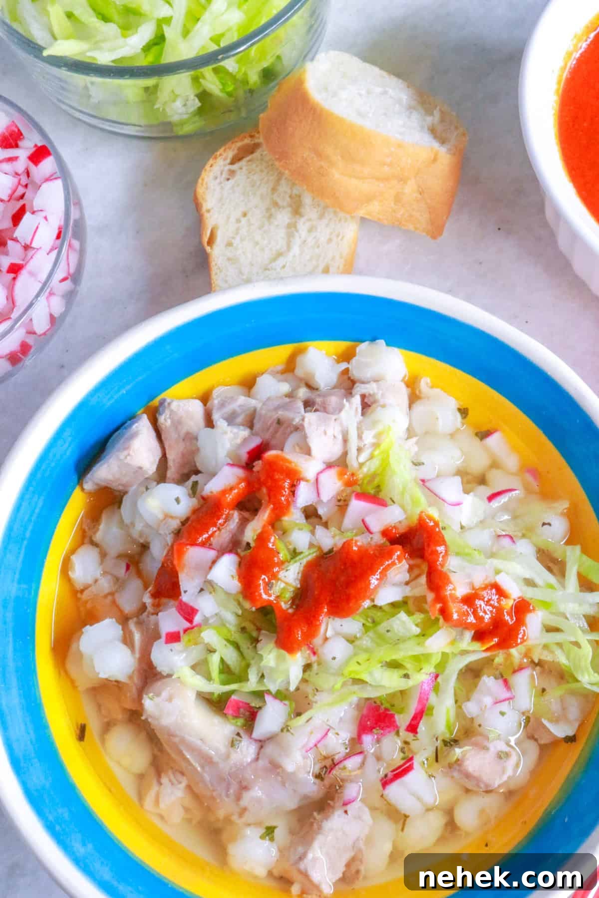 Bowl of pozole blanco with a drizzle of red chile sauce