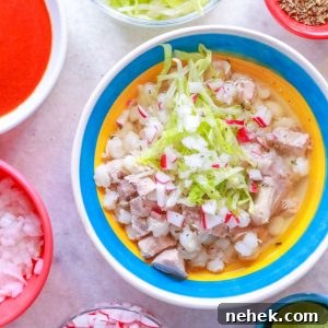 Bowl of Pozole Blanco with garnishes surrounded by small bowls with various garnishes