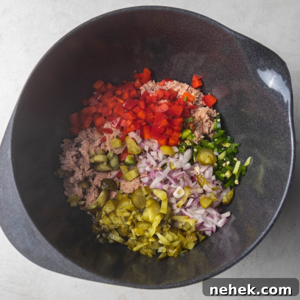 Gray bowl with tuna fish, diced red onion, diced red bell pepper, diced jalapeño, and diced pickle. 