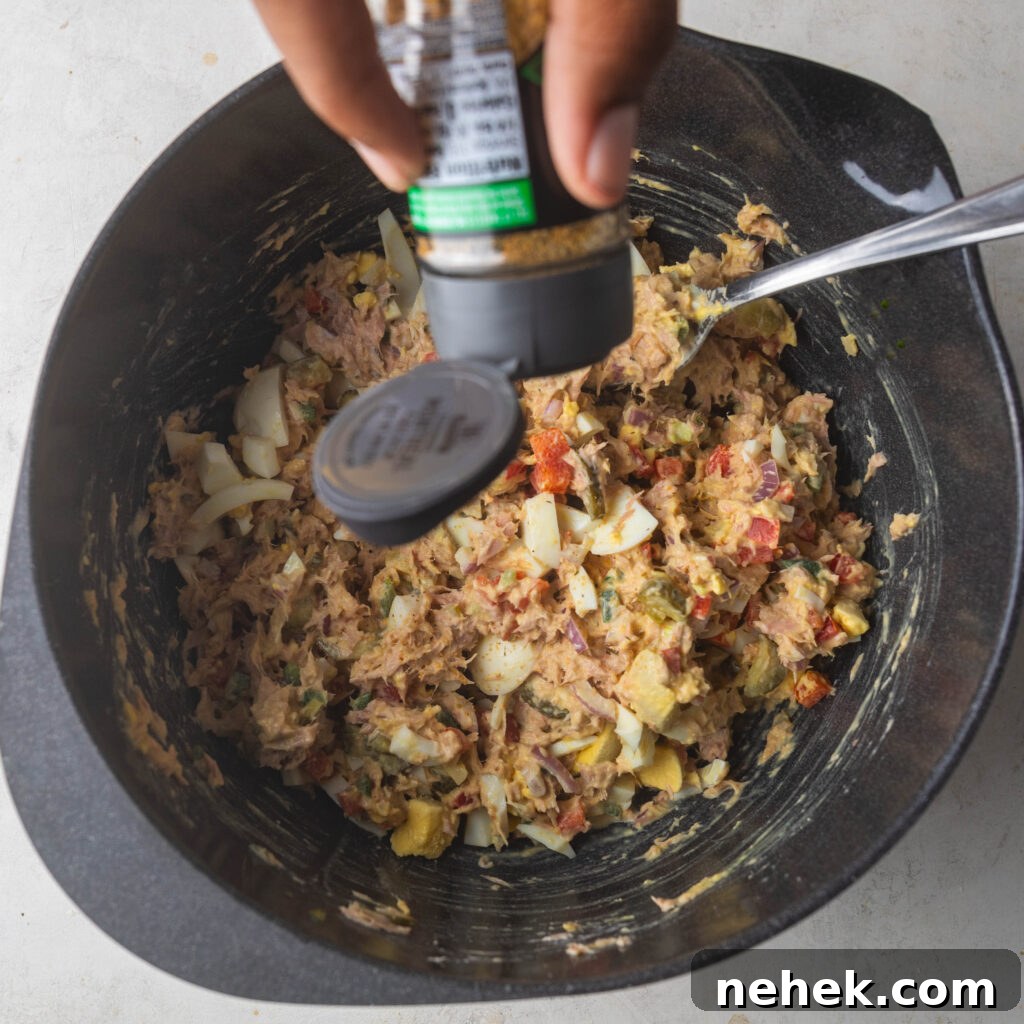 Adding seasoning to Spicy Tuna Salad mix