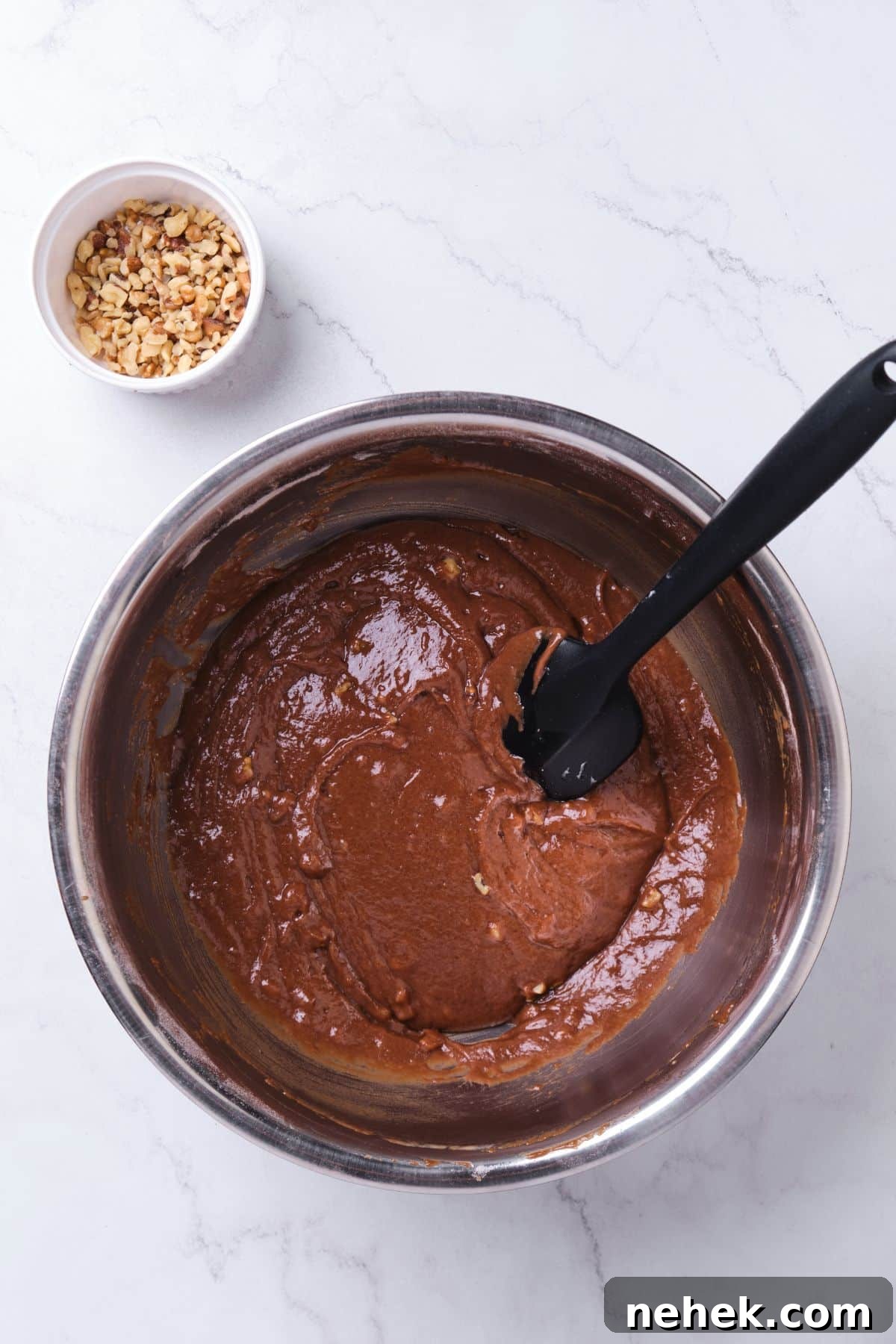 Chocolate cake batter in a bowl with a spatula.
