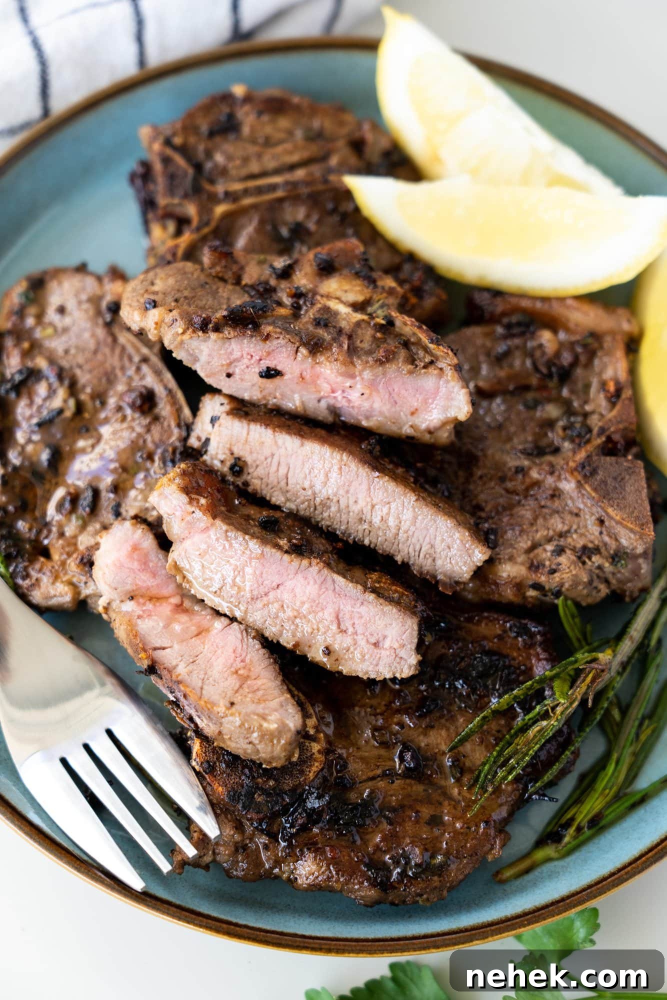 Crispy Pan-Seared Lamb Chops with Garlic Herb Butter 2 Stack of pan seared lamb chops on a blue plate. One cut to show a pink inside and crusty seared outside.