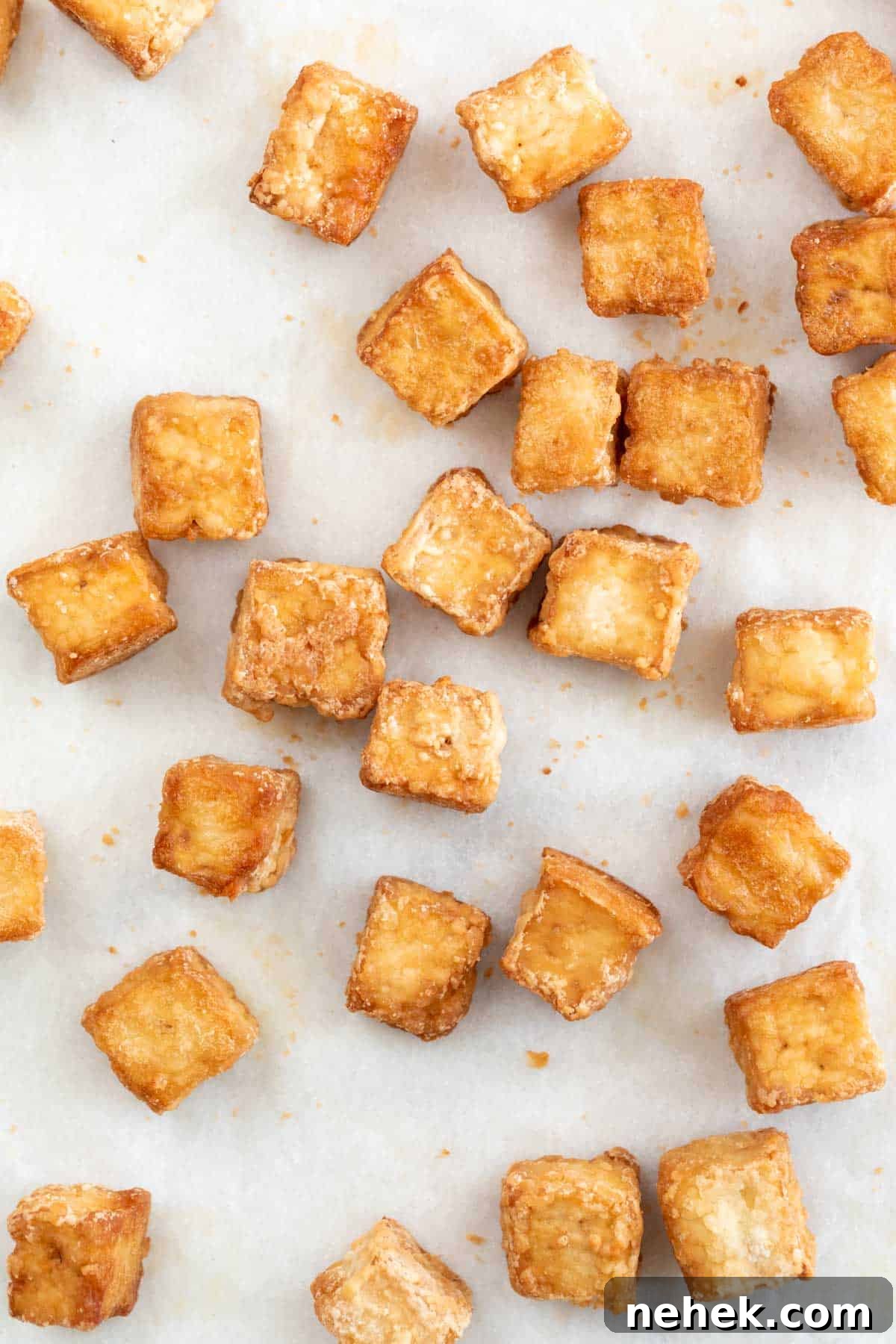 Crispy Oven-Baked Tofu with Golden Crunch 2 Overview of baked tofu cubes onto a lined baking sheet.