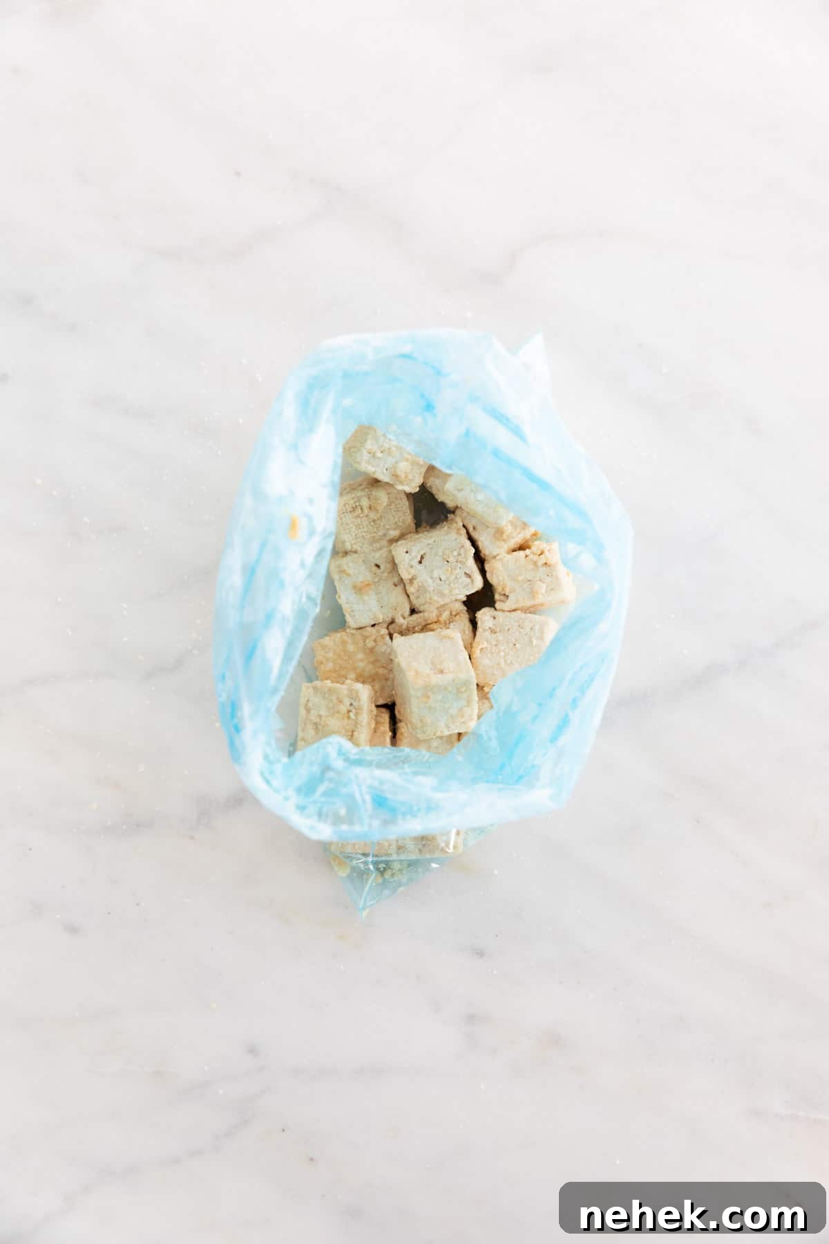 Crispy Oven-Baked Tofu with Golden Crunch 5 Tofu cubes coated in cornstarch inside a freezer bag.