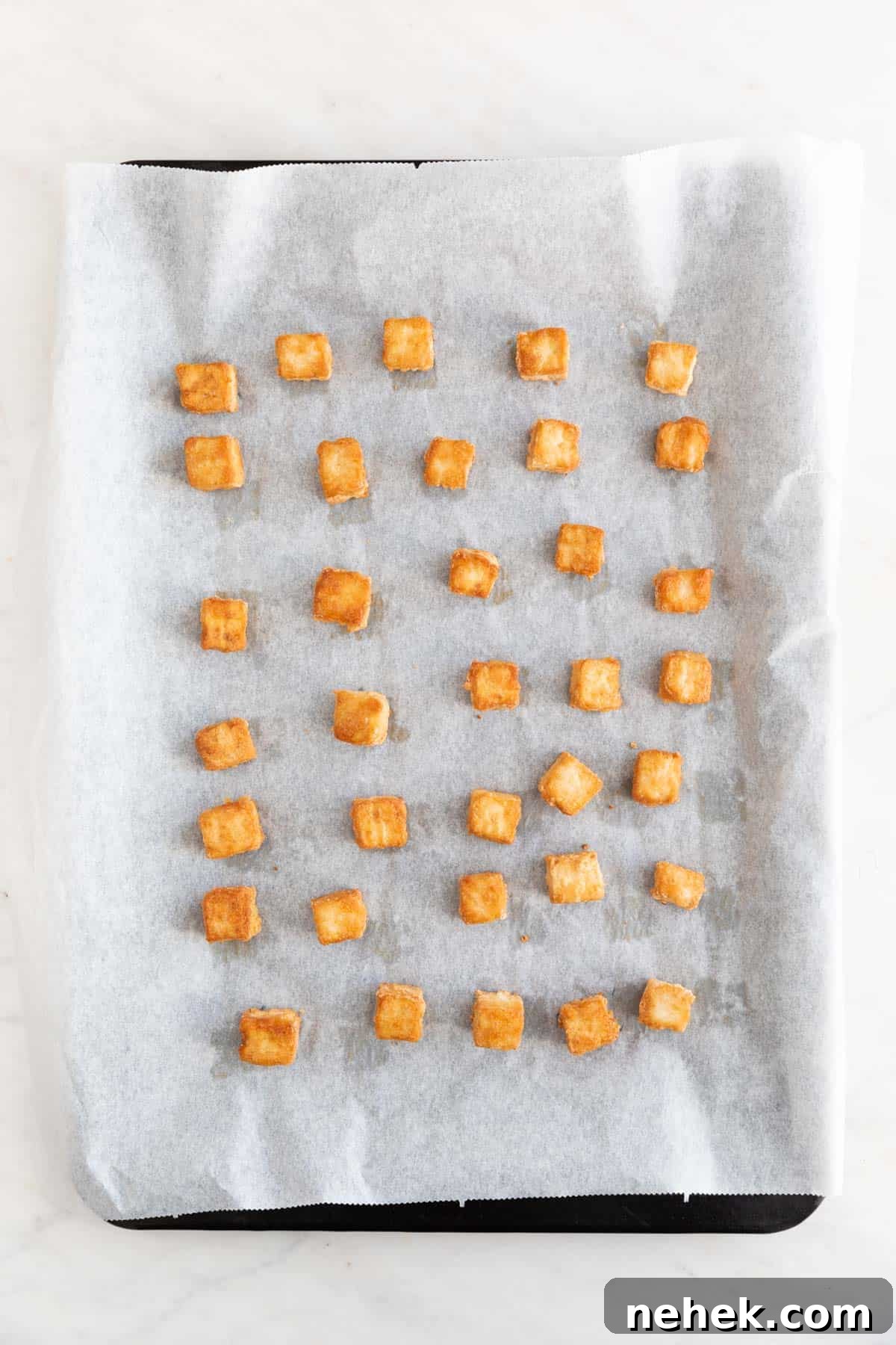 Crispy Oven-Baked Tofu with Golden Crunch 7 Tofu cubes onto a lined baking sheet after baking.