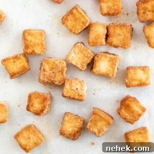 Crispy Oven-Baked Tofu with Golden Crunch 9 Overview of baked tofu cubes onto a lined baking sheet.