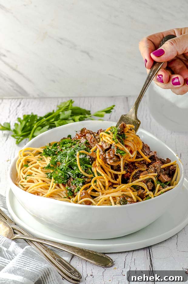 High-Protein Mushroom Pasta Recipe for Muscle & Energy 6 Side view of a bowl of mushroom pasta. There is a hand taking a forkful of pasta out of the bowl.