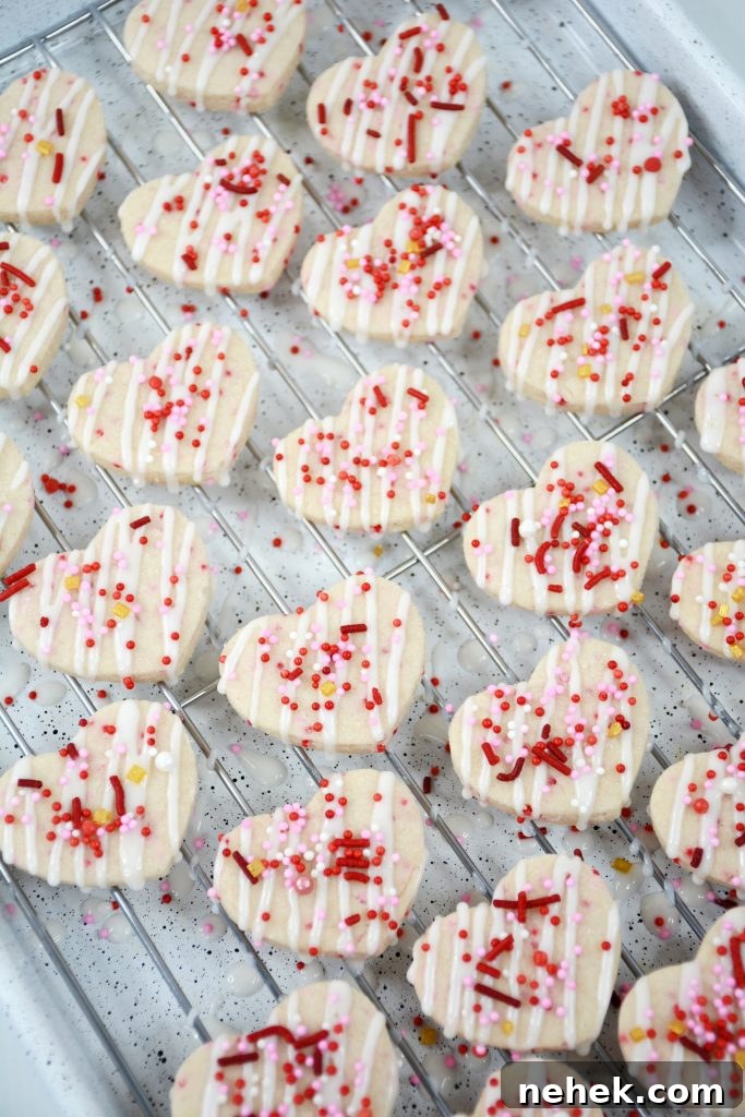 Mini Valentine Shortbread Cookies Recipe for Cute Heart Treats 6 sprinkles being added to the top of shortbread cookies on a wire rack.