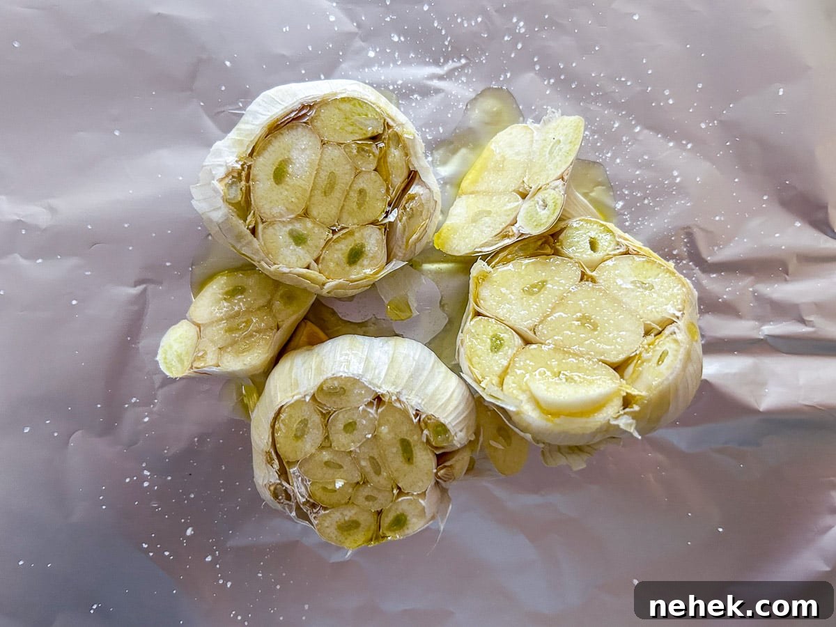 overhead view of raw heads of garlic, oil, and salt on foil