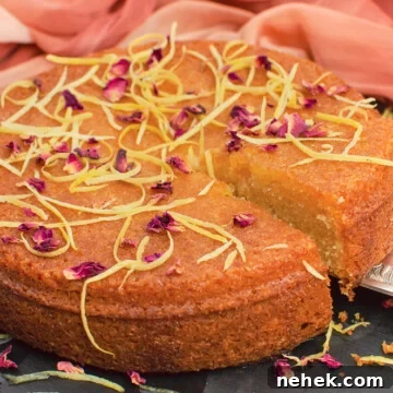Perfect Lemon Drizzle Cake Recipe — Moist, Zesty Slice 3 Slice of flawless lemon drizzle cake being lifted up with a silver cake knife