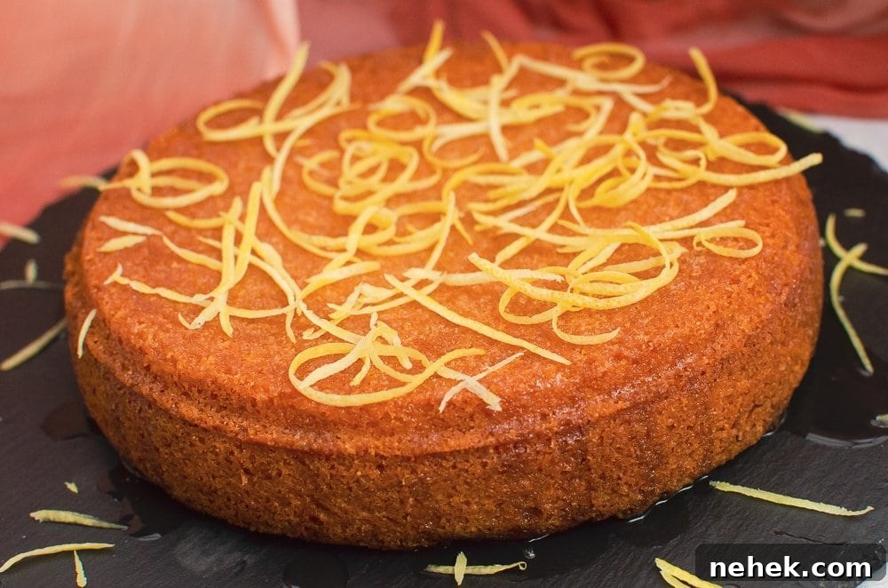 Perfect Lemon Drizzle Cake Recipe — Moist, Zesty Slice 24 Lemon zest being sprinkled over this easy round lemon drizzle cake