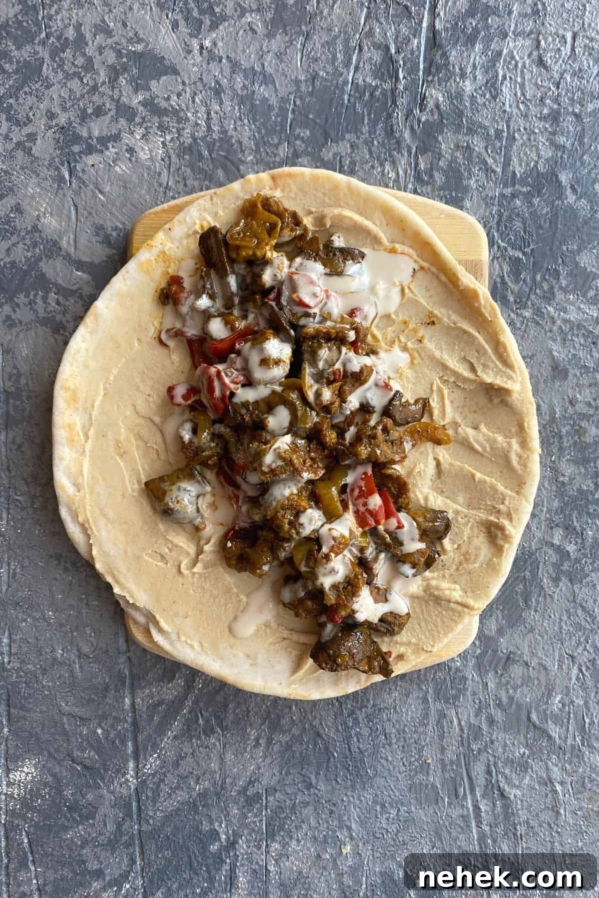 Mediterranean Vegan Sandwich with Roasted Veggies and Hummus 7 An overhead view of an open pita with all of the toppings to make a mediterranean vegan sandwich in it