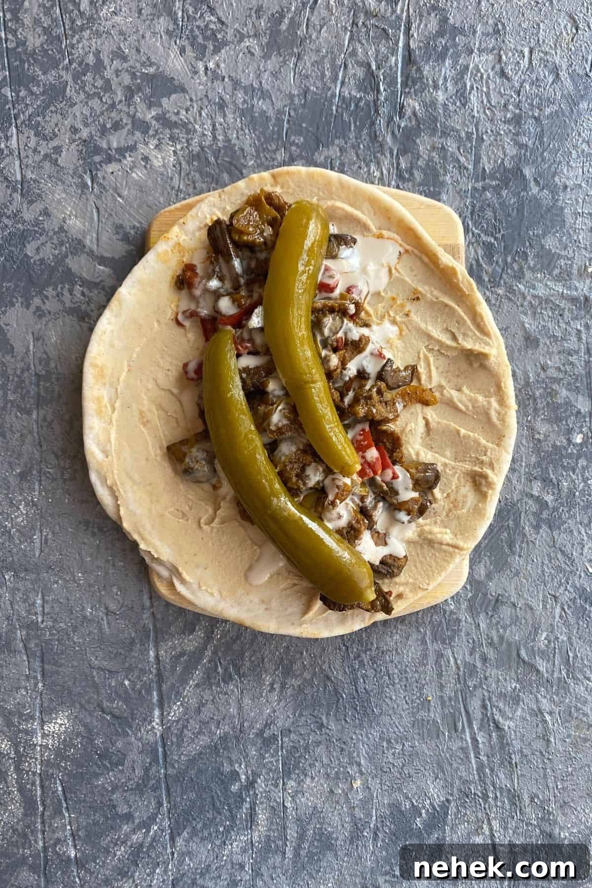 Mediterranean Vegan Sandwich with Roasted Veggies and Hummus 8 An overhead view of an open pita with all of the toppings to make a mediterranean vegan sandwich in it