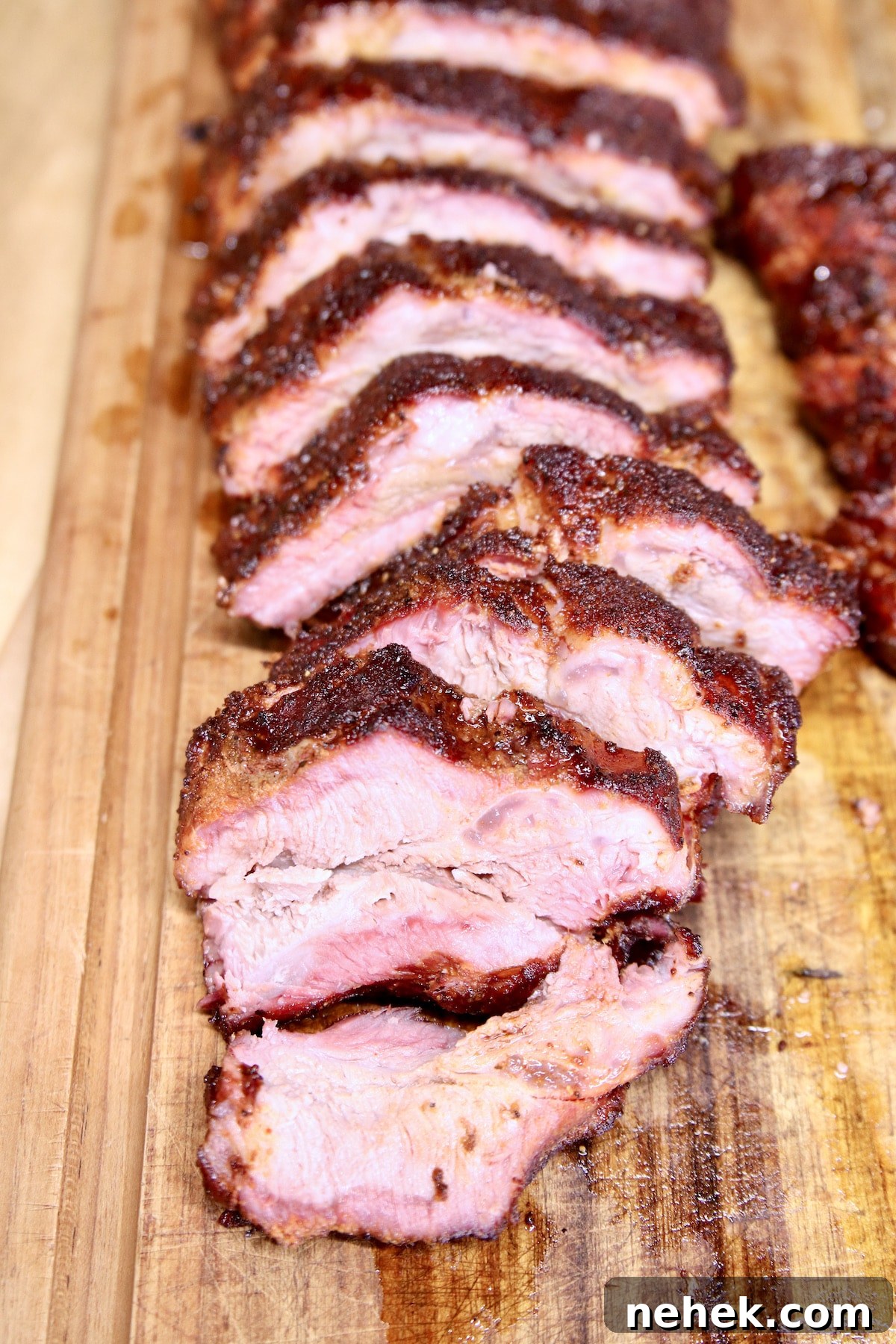 Smoky baby back ribs recipe made on the grill. Sliced baby back ribs on a cutting board.