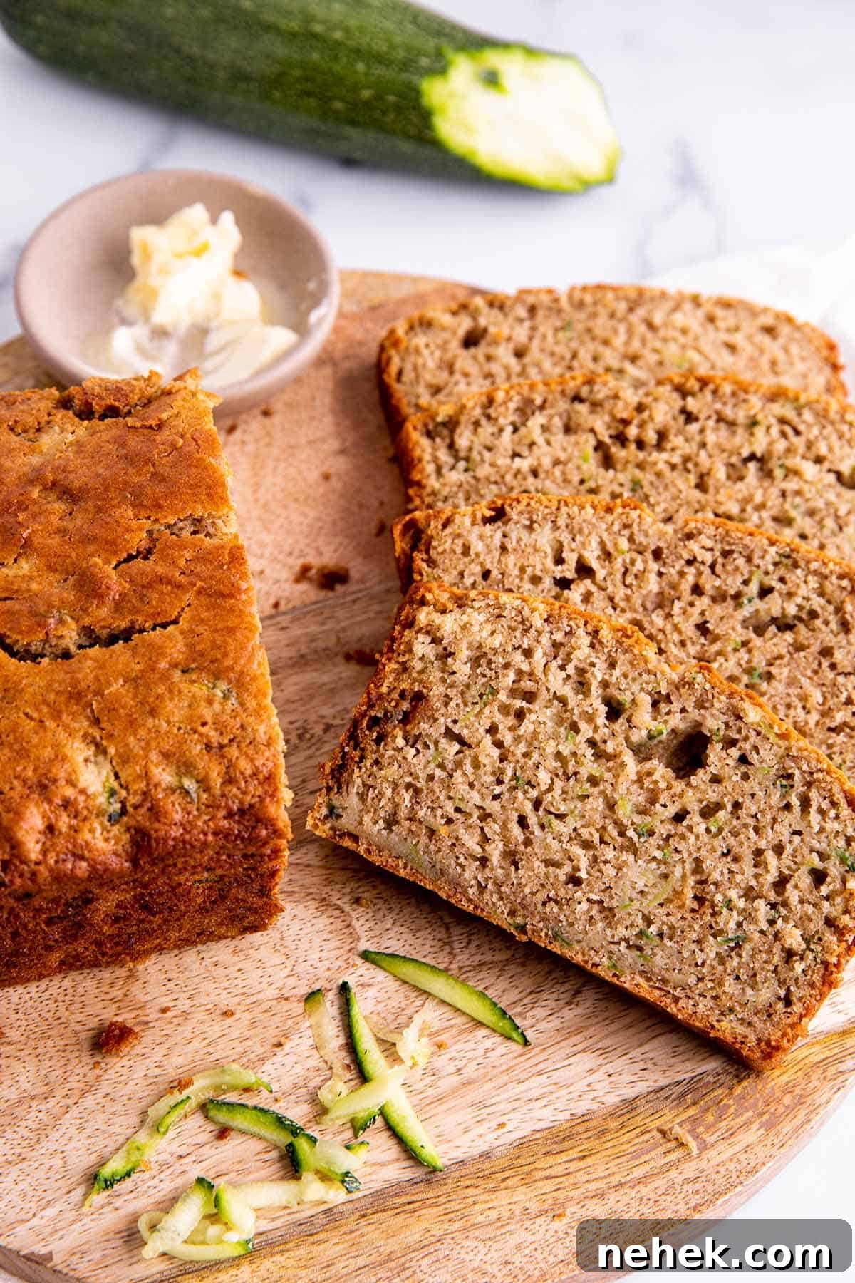 Moist Sourdough Zucchini Bread Recipe 6 Slices of zucchini bread on a wooden board with shreds of zucchini.
