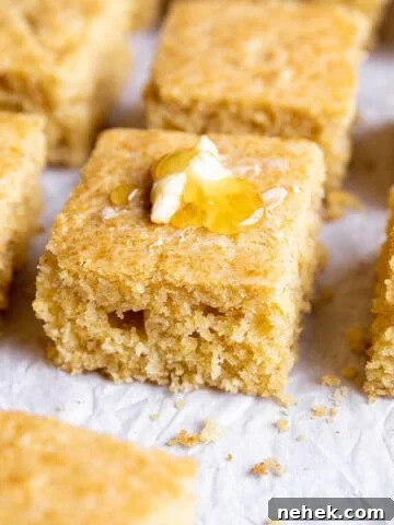 A piece of sourdough cornbread with some butter and honey on top.