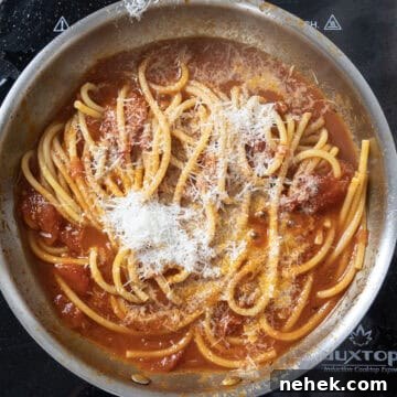 Authentic Bucatini Amatriciana Recipe 11 Bucatini combined with sauce and topped with pecorino in sauce pan.