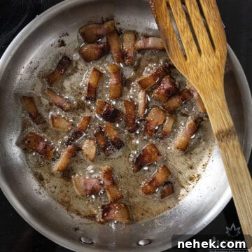 Authentic Bucatini Amatriciana Recipe 7 Golden brown guanciale frying in a saucepan.