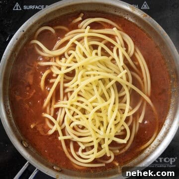 Authentic Bucatini Amatriciana Recipe 10 Bucatini pasta added to sauce in saucepan.