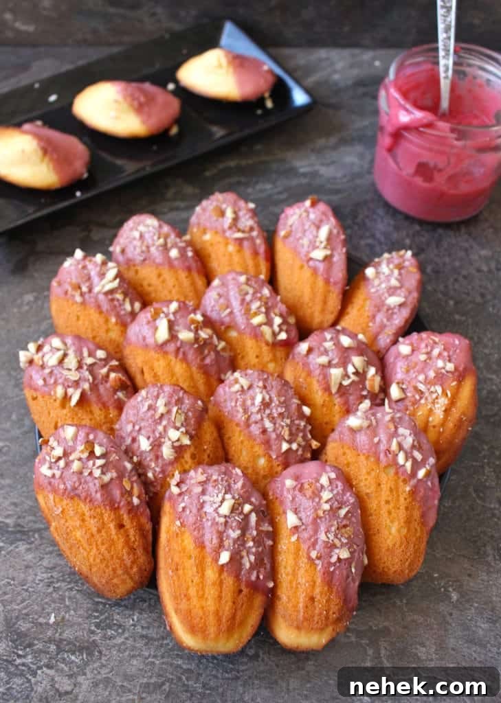 Almond Madeleines with Raspberry Glaze Recipe 6 Cakes placed next to each other on their back over a black plate