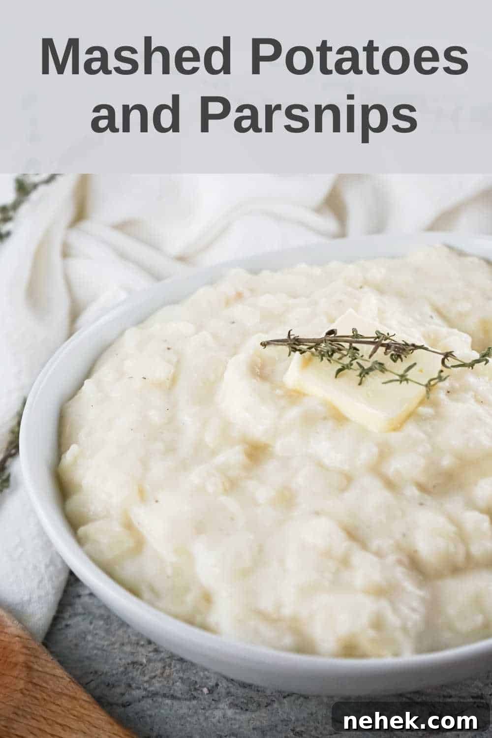 Creamy Mashed Potatoes and Parsnips Recipe 2 Close up shot of potato and parsnip mash with a pad of butter and herbs in a white bowl on a white cloth.
