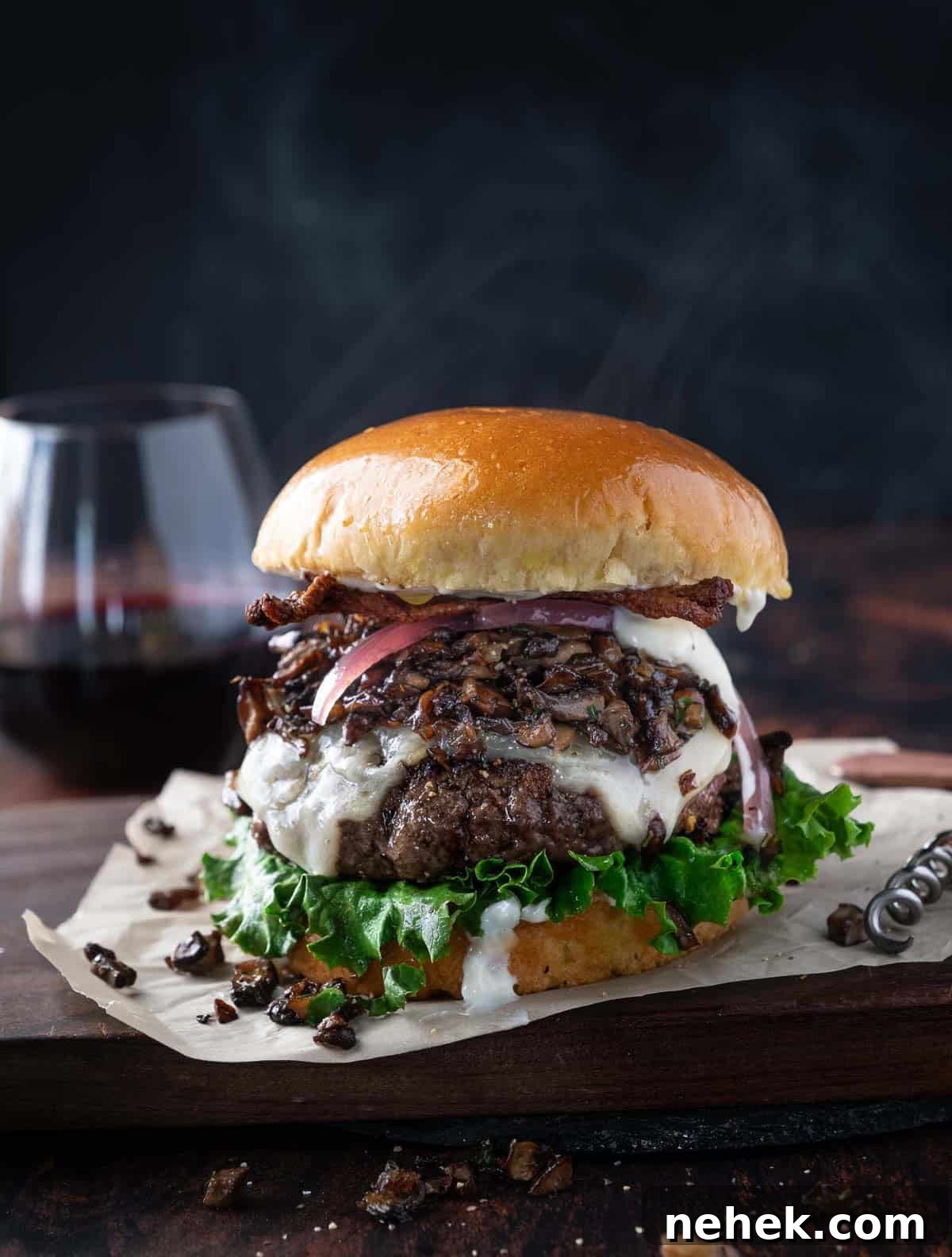 Gourmet Wild Mushroom Burger Recipe 2 A Gourmet Burger topped with Sautéed Wild Mushrooms on a serving platter with a glass of red wine.