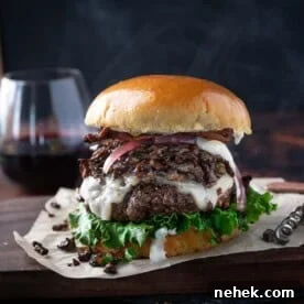 A Gourmet Burger topped with Sautéed Wild Mushrooms on a serving platter with a glass of red wine.