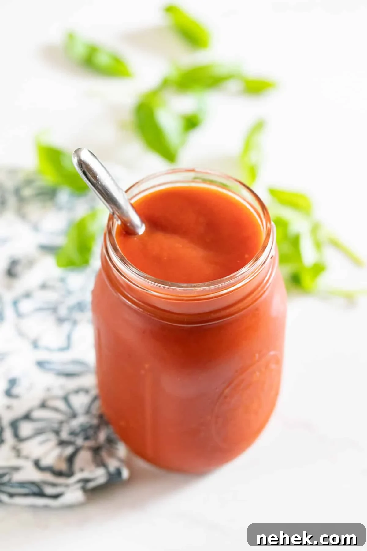 Homemade Sugar-Free Marinara Sauce 2 A jar of red sauce with a spoon in it and a napkin next to it.