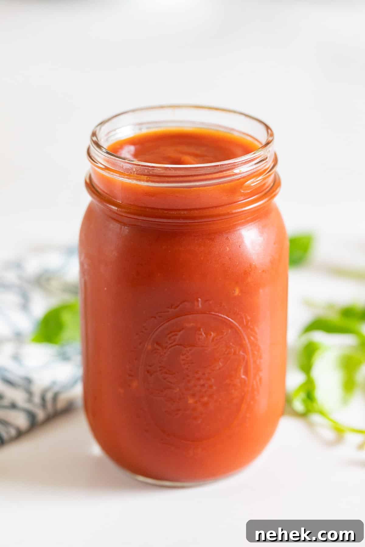 Homemade Sugar-Free Marinara Sauce 8 A jar of tomato sauce with fresh basil behind it.
