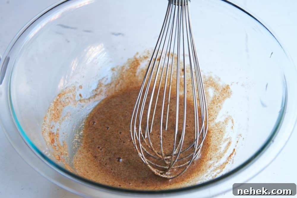 Sweet and Spiced Roasted Nuts 3 Egg white with spices in a glass bowl with a whisk.