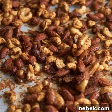 Sweet and Spiced Roasted Nuts 7 Spiced mixed nuts on white parchment paper.