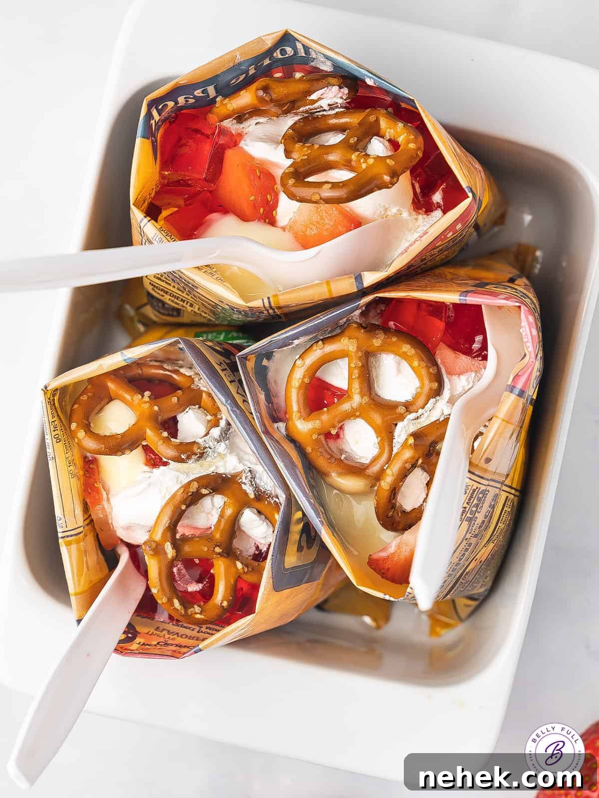 Made with cheesecake pudding, strawberry jello, whipped cream, and pretzels, this Walking Strawberry Pretzel Salad is a fun, portable dessert. Overhead view of walking strawberry pretzel salad standing up in a baking dish